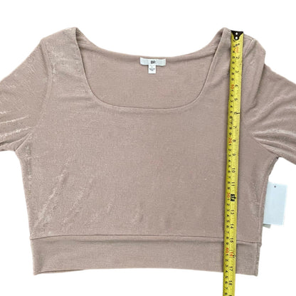 A women's scoop-neck crop top in a light pink color, shown flat with a yellow tape measure and retail tag for size reference.