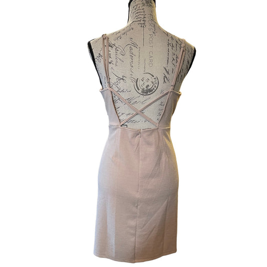 A sleeveless light beige  displayed on a vintage-style dress form mannequin, showing the back design with thin crisscross straps and a straight skirt, set against a plain white background.