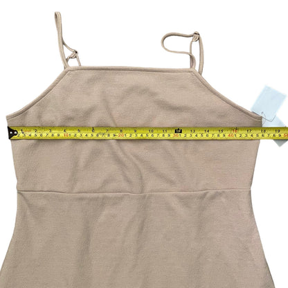 A beige spaghetti-strap dress with a yellow tape measure stretched horizontally across the chest to show the bust measurement, on a white background.