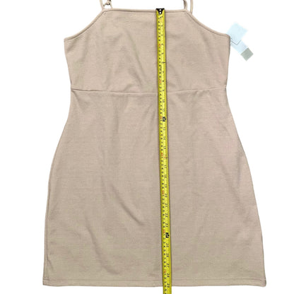 A beige sleeveless  dress shown flat against a white background, with a yellow measuring tape vertically aligned down the center to indicate its height. A small light blue tag is visible near the shoulder.