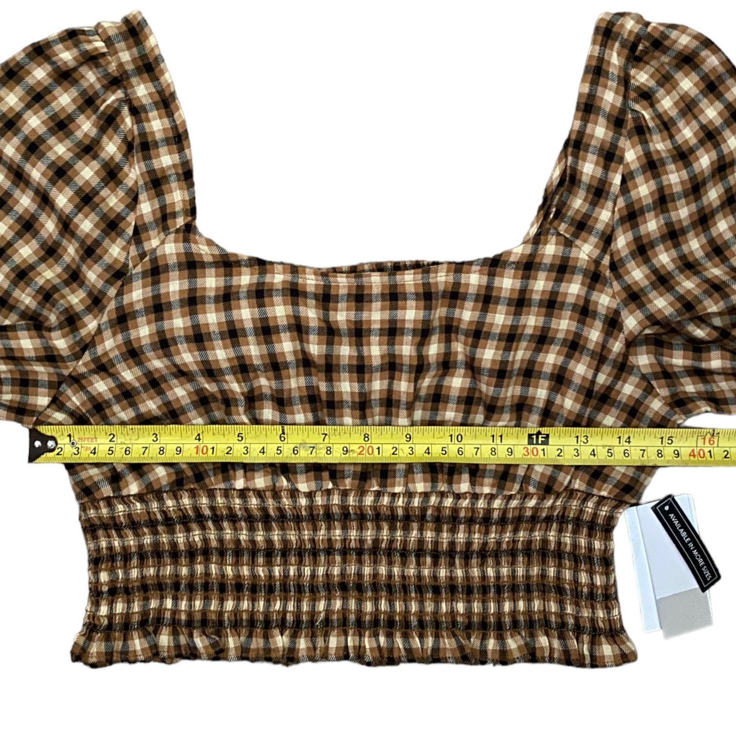 Plaid top with a measuring tape for size reference on a white background