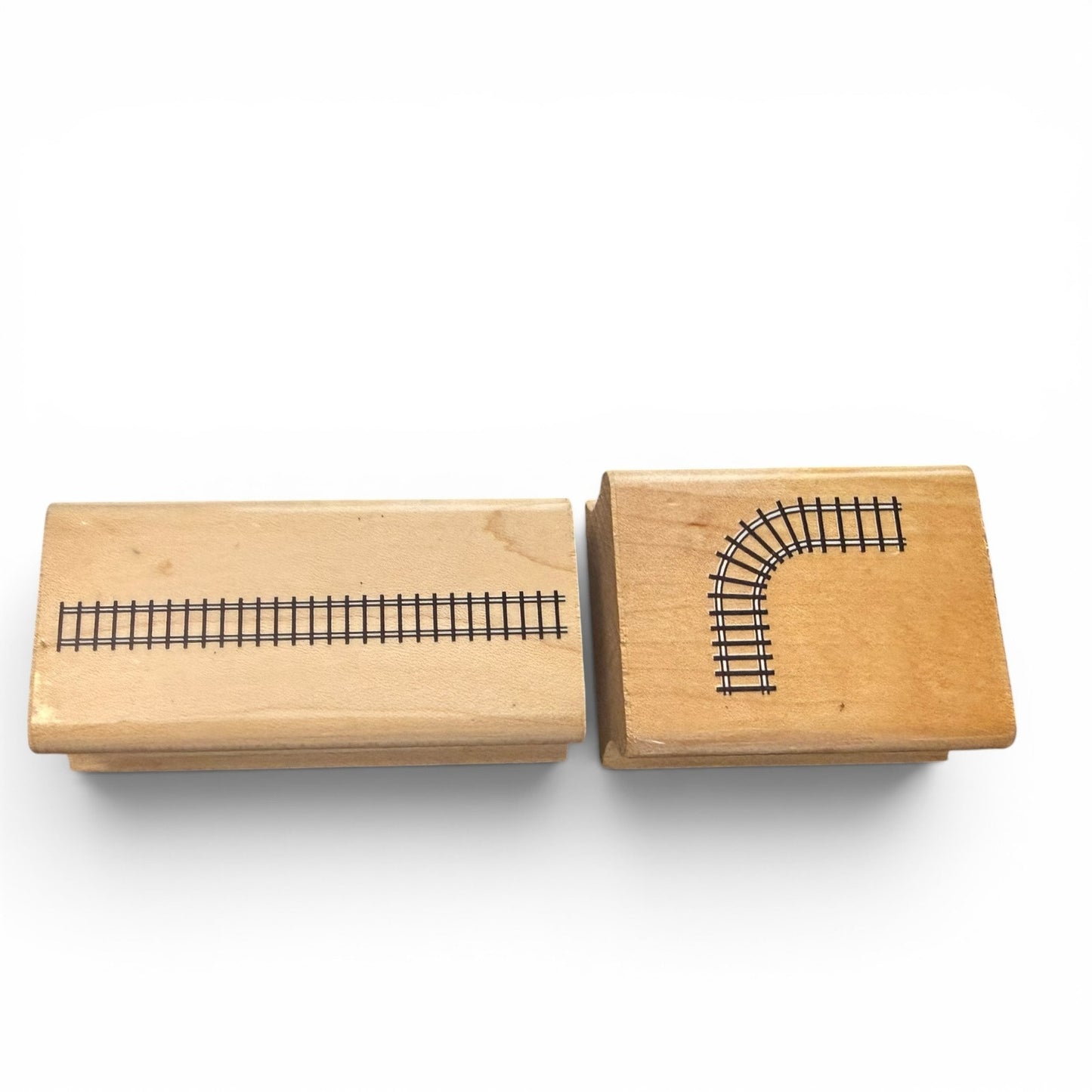 Two wooden stamps with train track designs on a white background