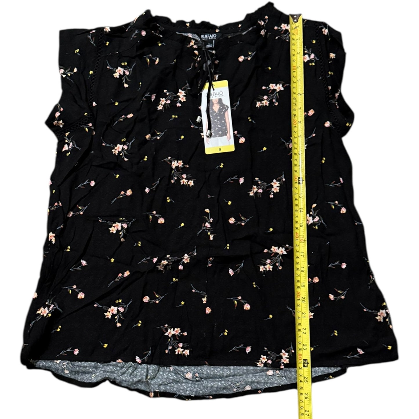 Black floral sleeveless top with a measuring tape on a white background