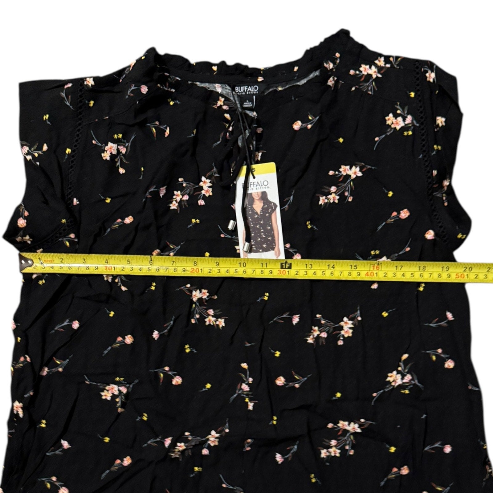Black floral top with a measuring tape and tag on a white background