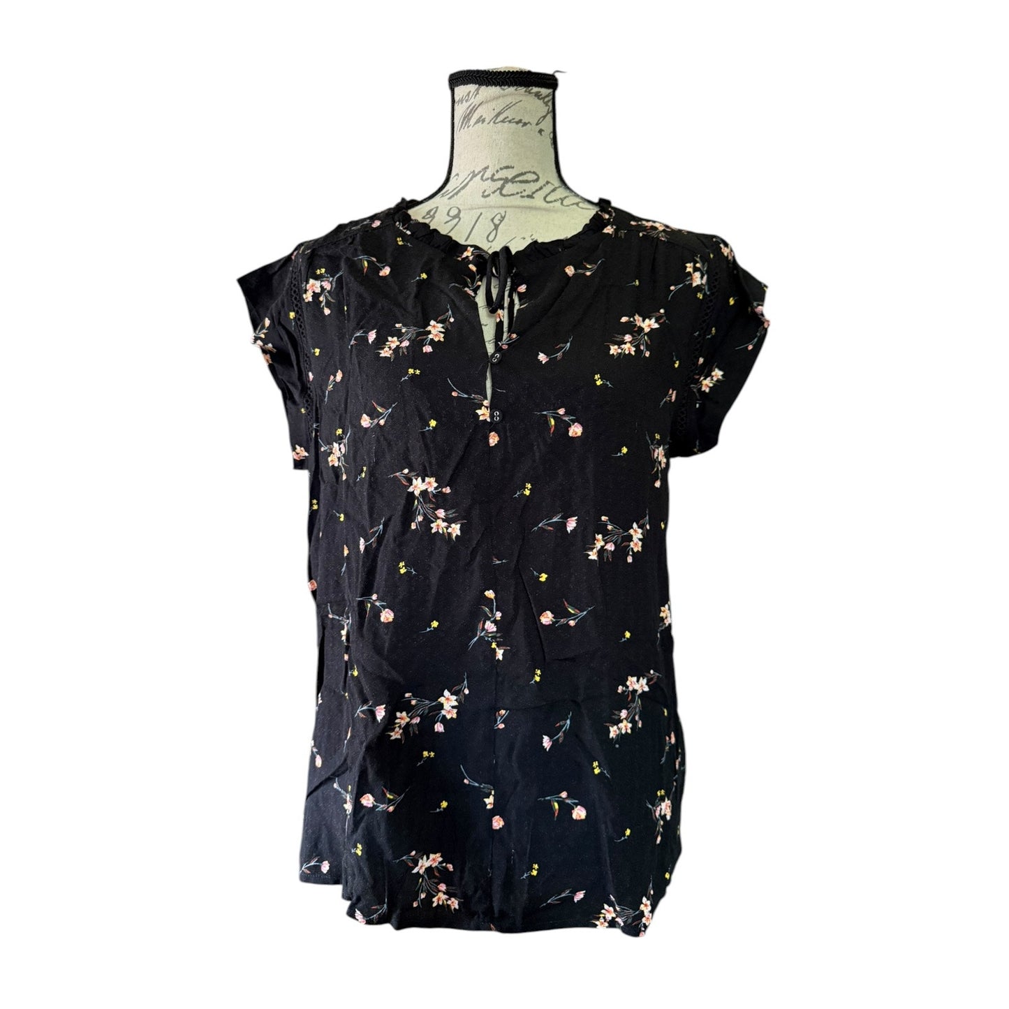 Black floral blouse on a mannequin against a white background