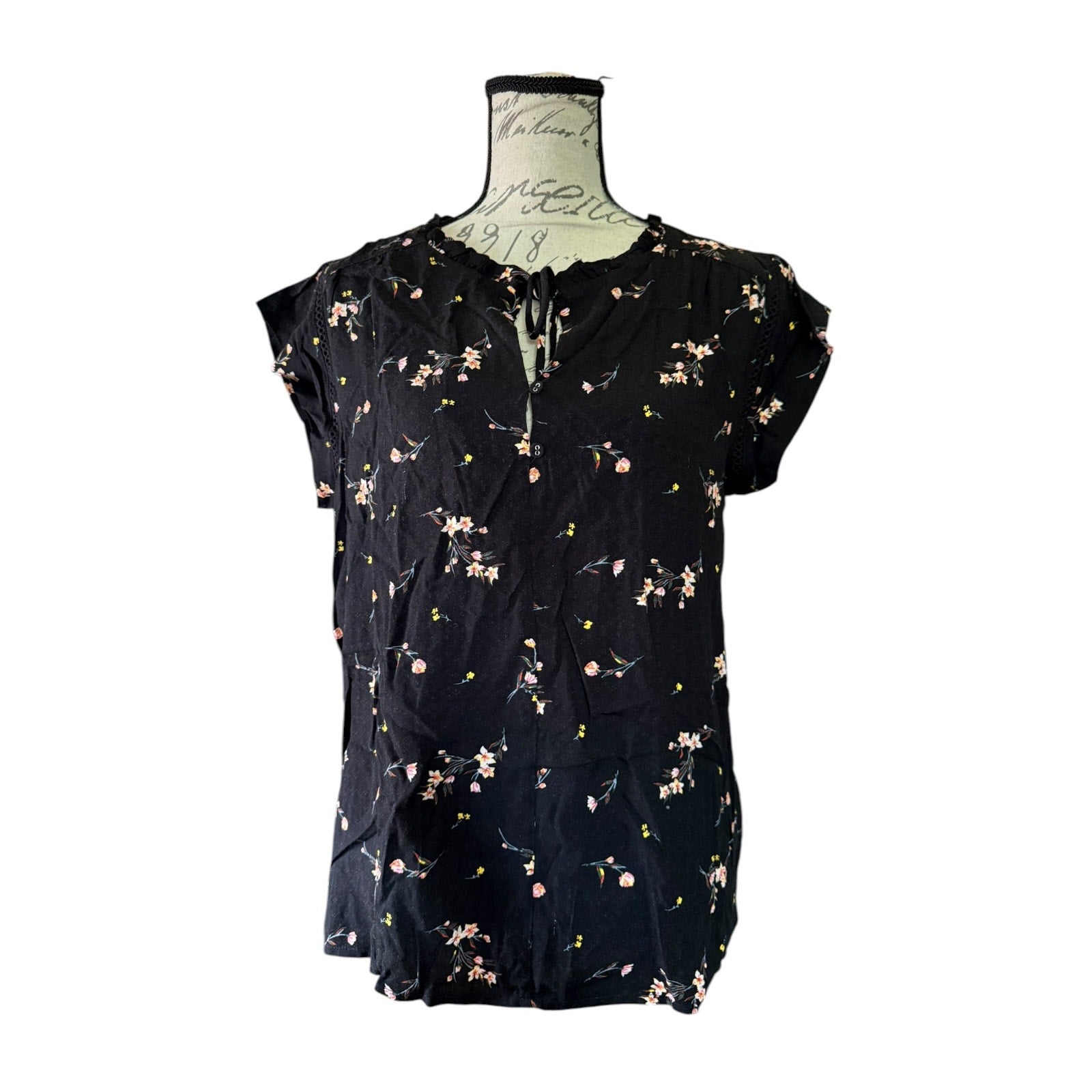 Black floral blouse on a mannequin against a white background