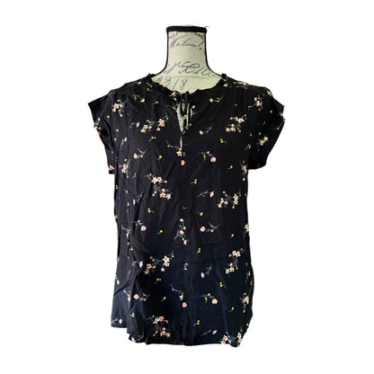 Black floral blouse on a mannequin against a white background