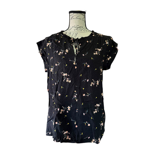 Black floral blouse on a mannequin against a white background