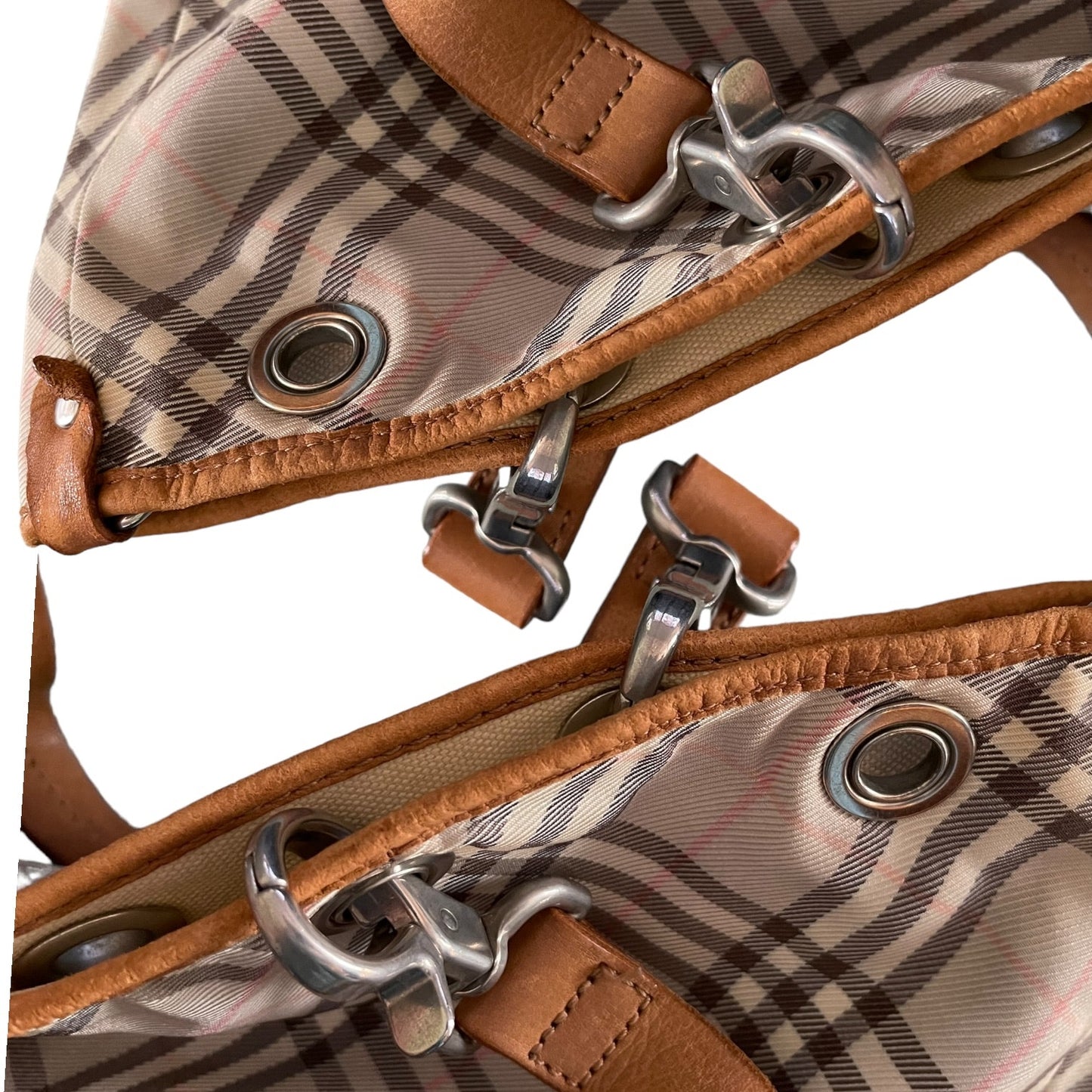 Close-up of a plaid fabric with brown leather straps and metal buckles on a white background.