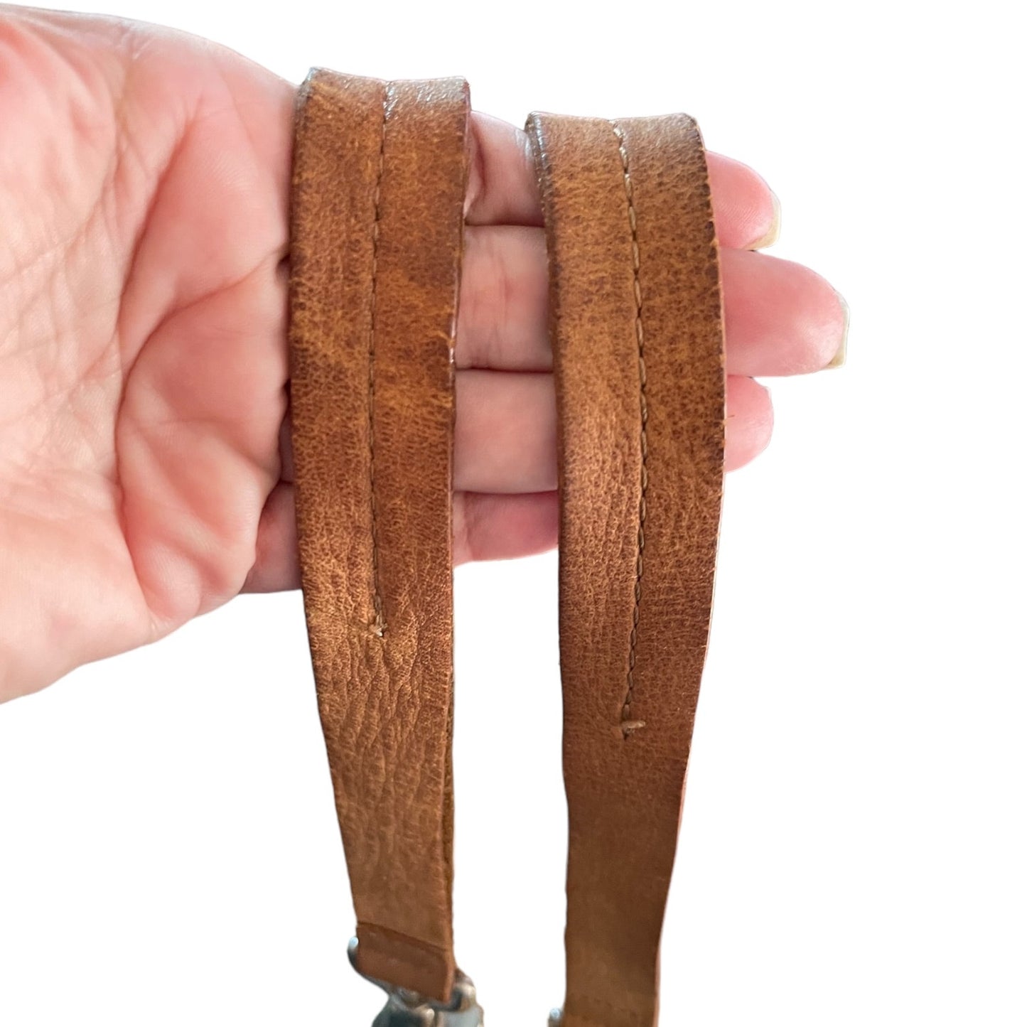 Brown leather strap held by a hand on a white background