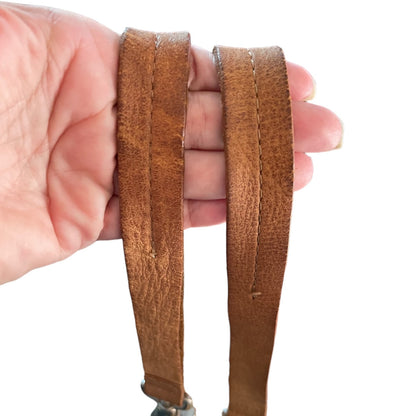 Brown leather strap held by a hand on a white background