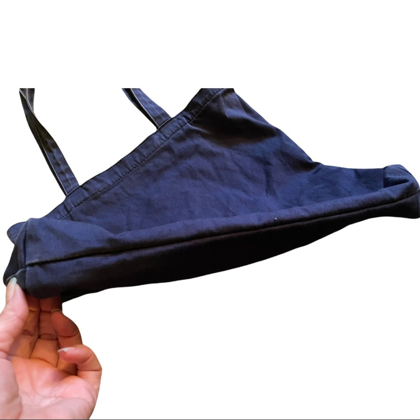 Bottom of blue bag held by a hand on a white background