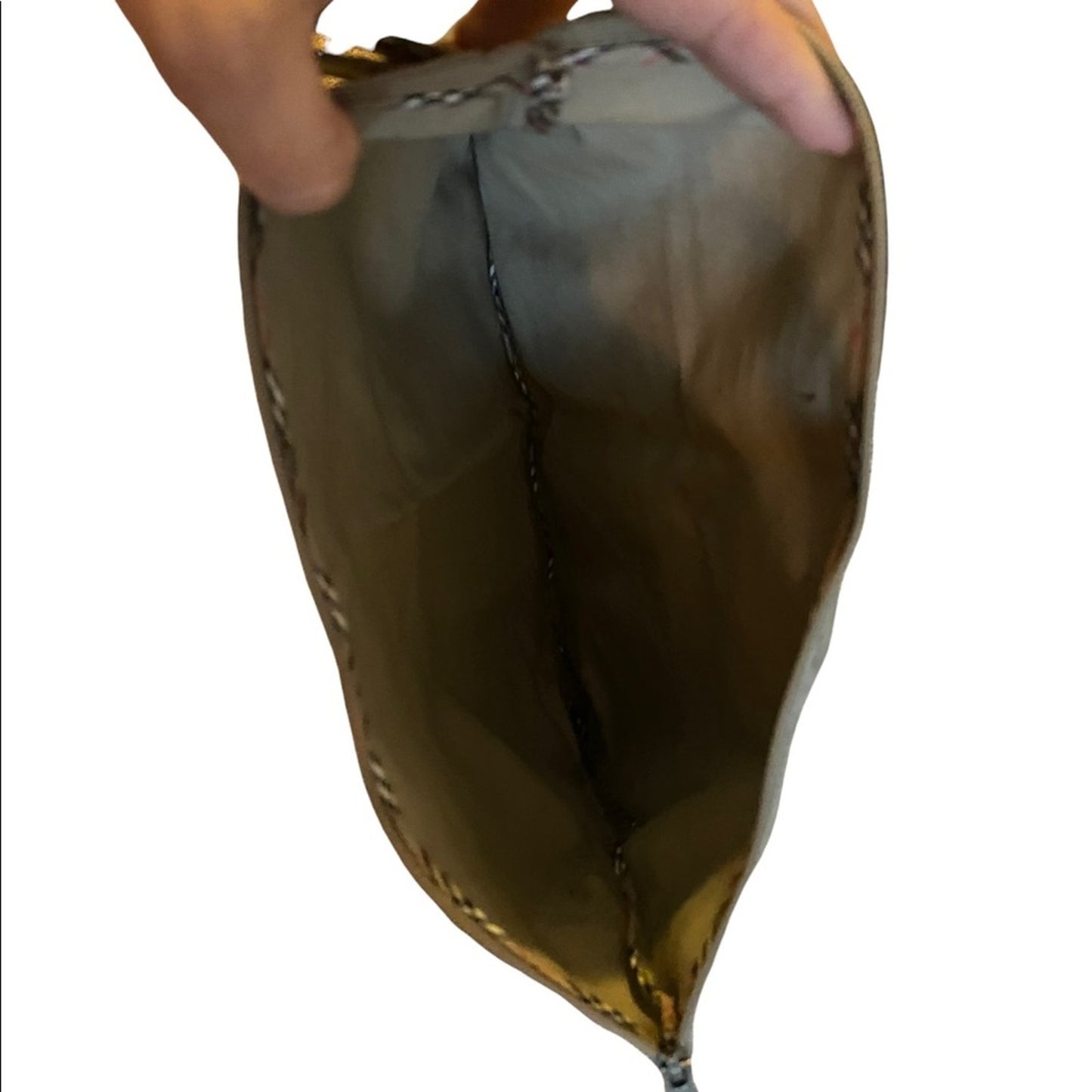 Inteiror of metallic pouch held by a hand on a white background