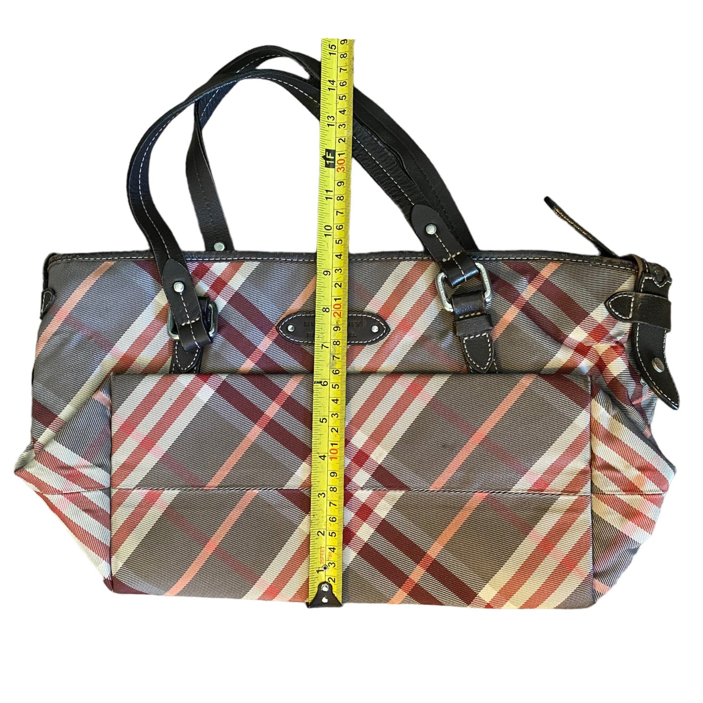 Plaid patterned handbag with a measuring tape for scale on a white background