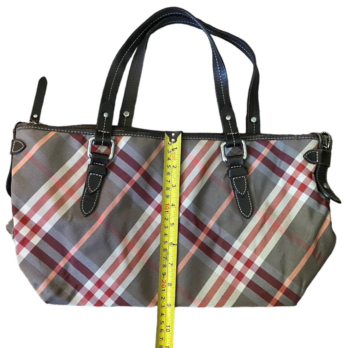 Plaid handbag with a measuring tape for scale on a white background