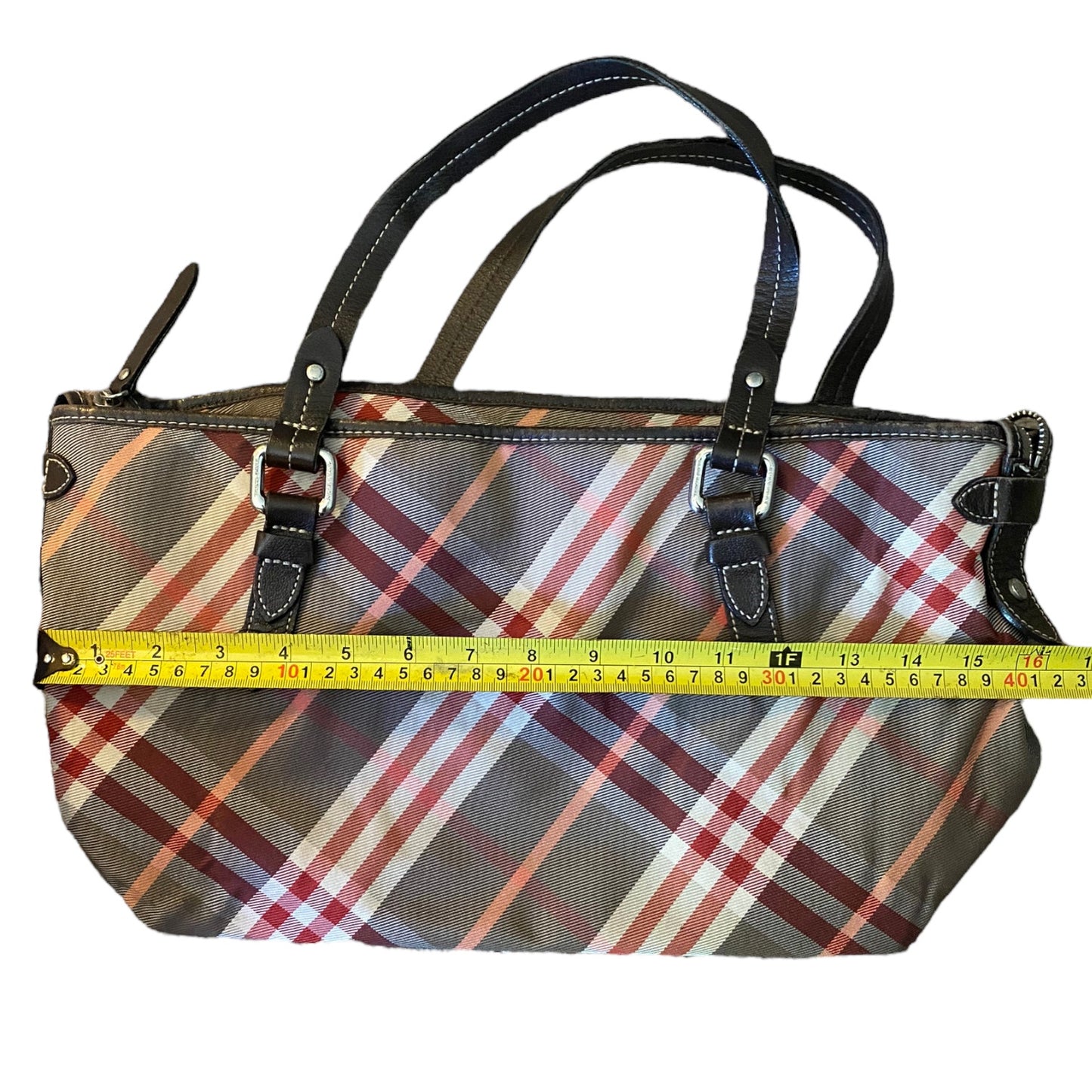 Plaid handbag with a measuring tape for size reference on a white background