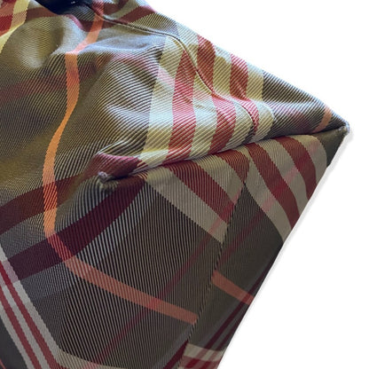 Corner of purse with red, black and beige colors on a white background