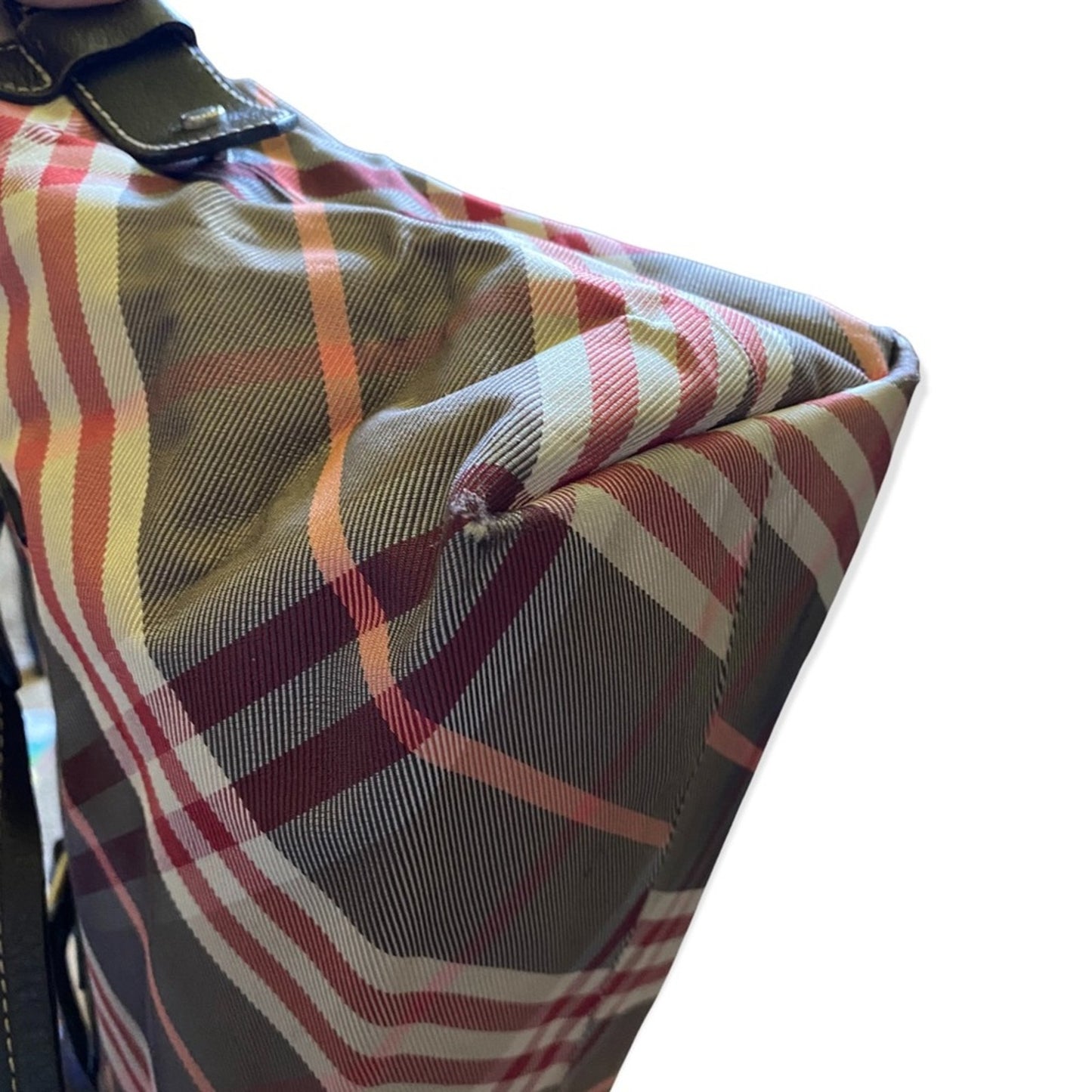 Corner of Plaid patterned bag with a strap on a white background
