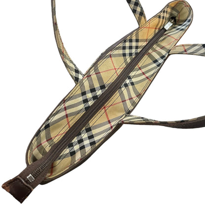 A close-up of a zippered tote with a beige plaid pattern featuring black, white, and thin red lines, plus dark brown trim and straps, shown on a plain white background.