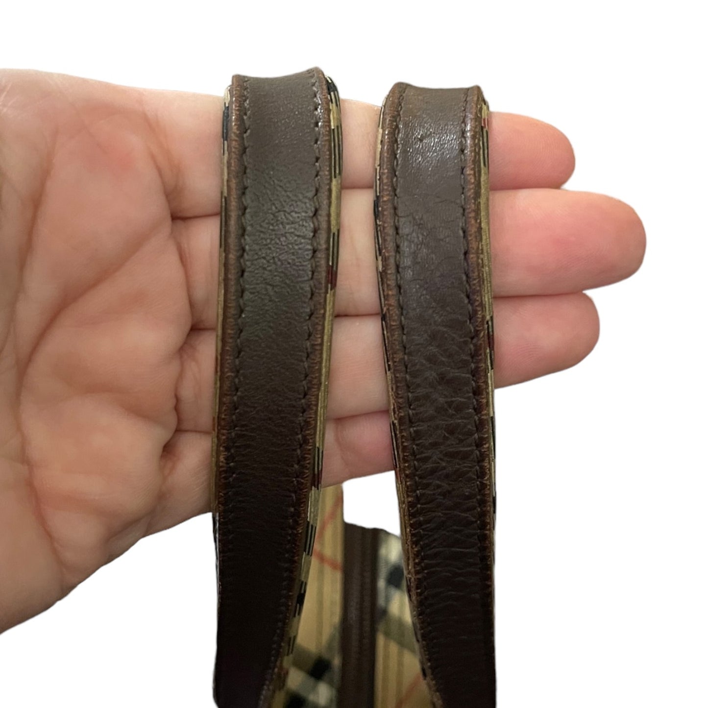 Brown leather handle held between fingers on a white background