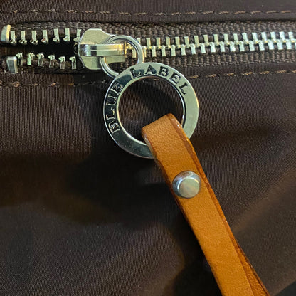 Close-up of a brown interior of bag with a leather strap and 'Blue Label' zipper pull.
