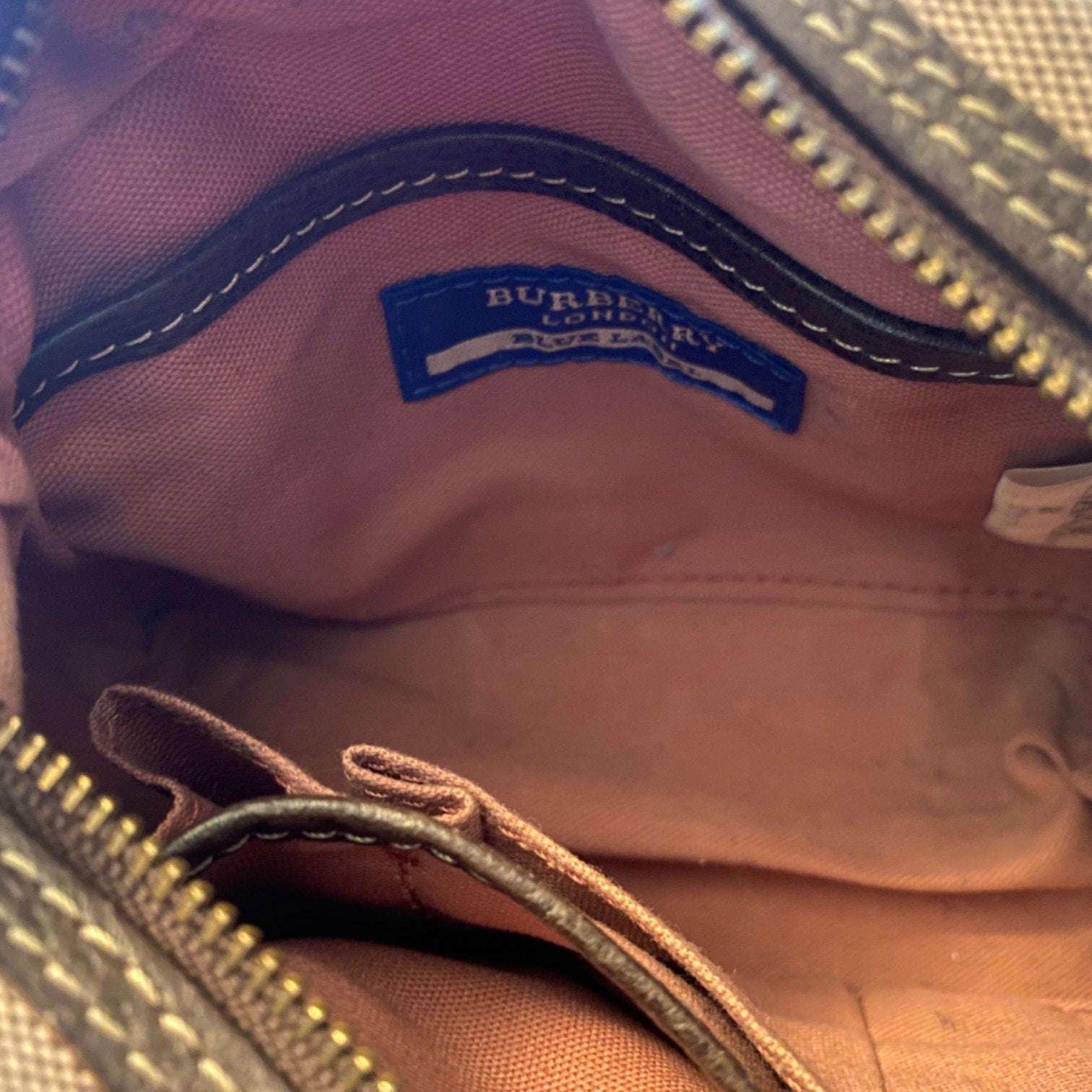 Close-up of interior of pink bag with a Burberry logo.