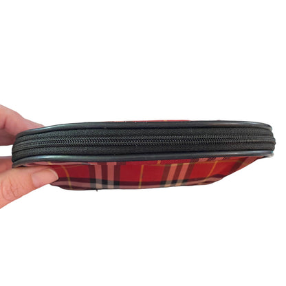 Red plaid pouch top with a black zipper held by a hand on a white background