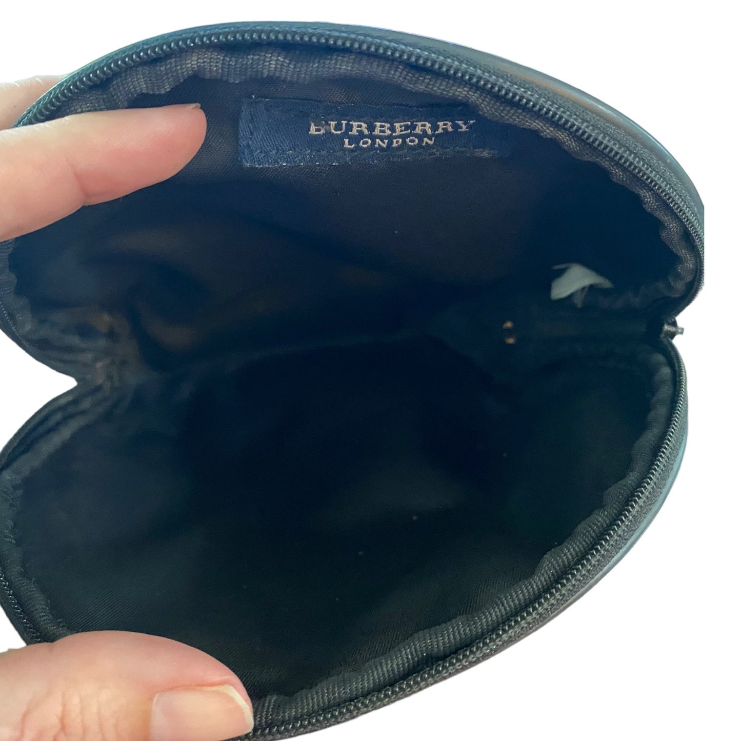 interior of Burberry pouch held open by a hand on a white background