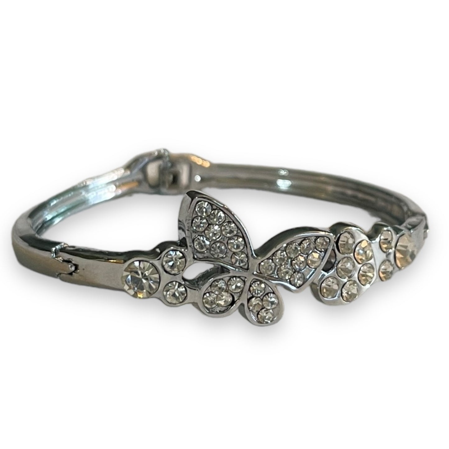 A silver-toned bangle bracelet featuring a butterfly and floral motif embellished with clear rhinestones, set against a plain white background.