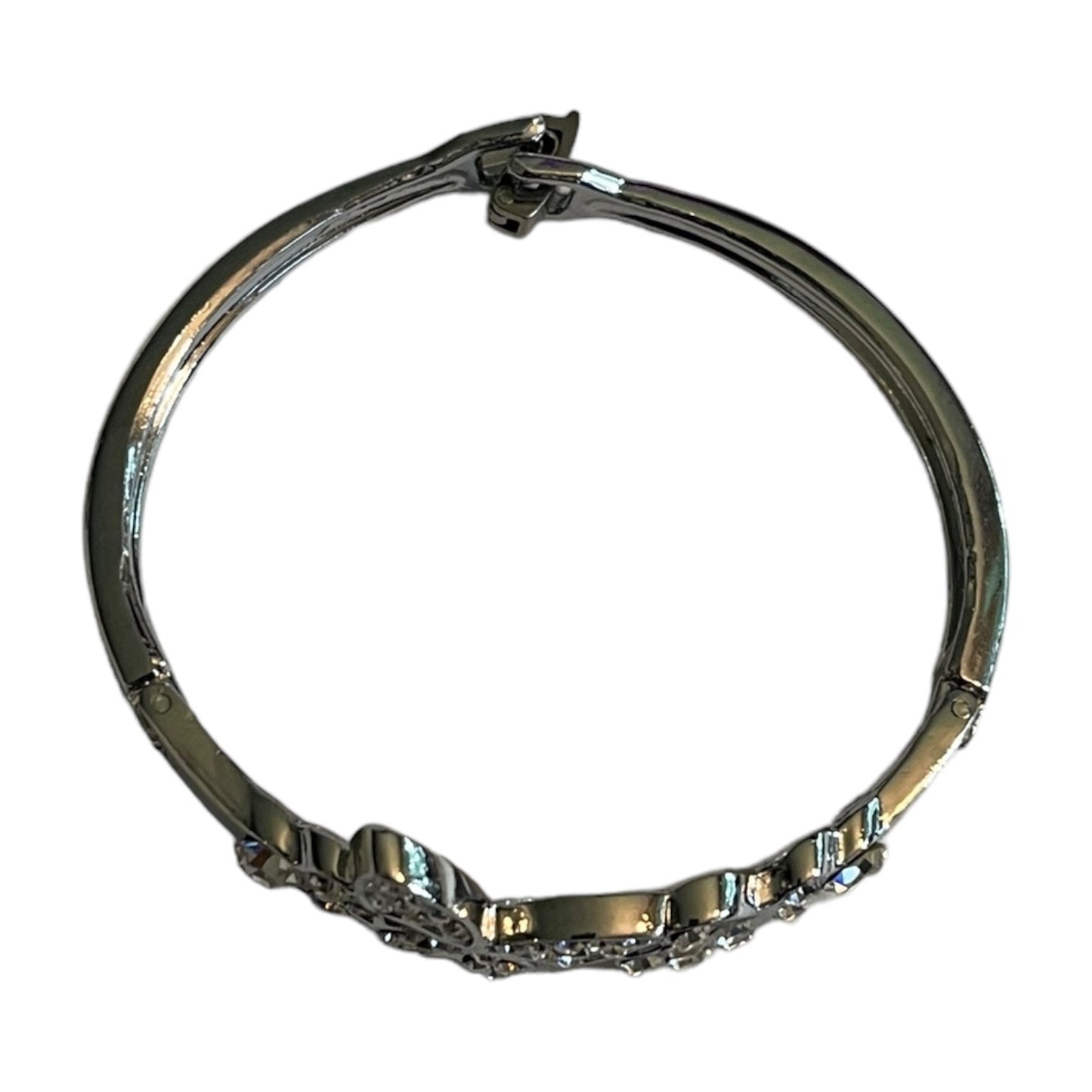 Top view of a polished silver-toned bangle bracelet with a decorative pavé crystal section on one side, shown against a plain white background.