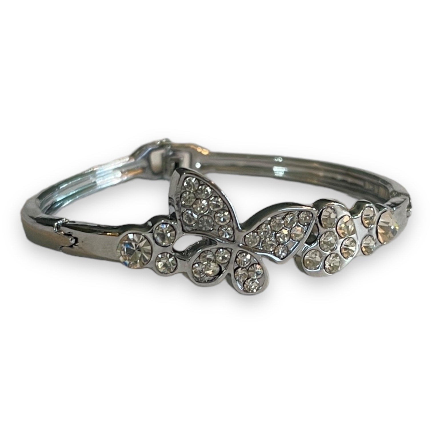A silver-toned bangle bracelet featuring a butterfly and floral motifs embellished with clear rhinestones, shown on a plain white background.