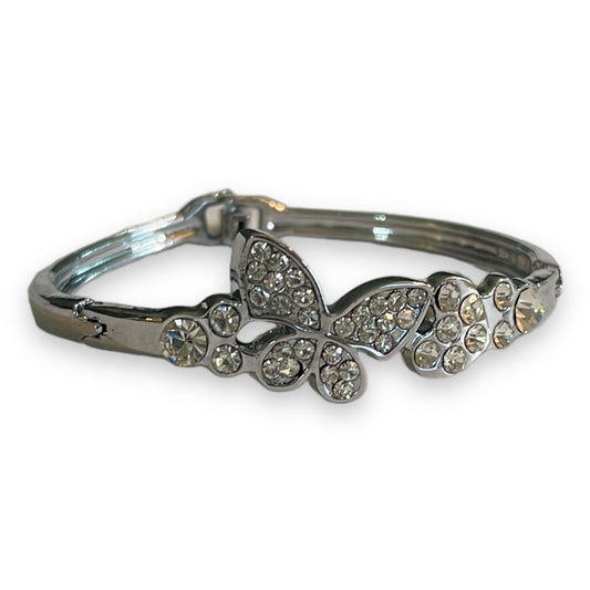 A silver-toned bangle bracelet featuring a butterfly and floral motifs embellished with clear rhinestones, shown on a plain white background.