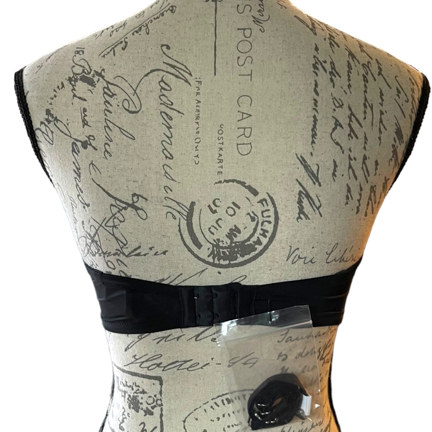 Back of black bra on Mannequin with vintage-style text and stamp design on a white background
