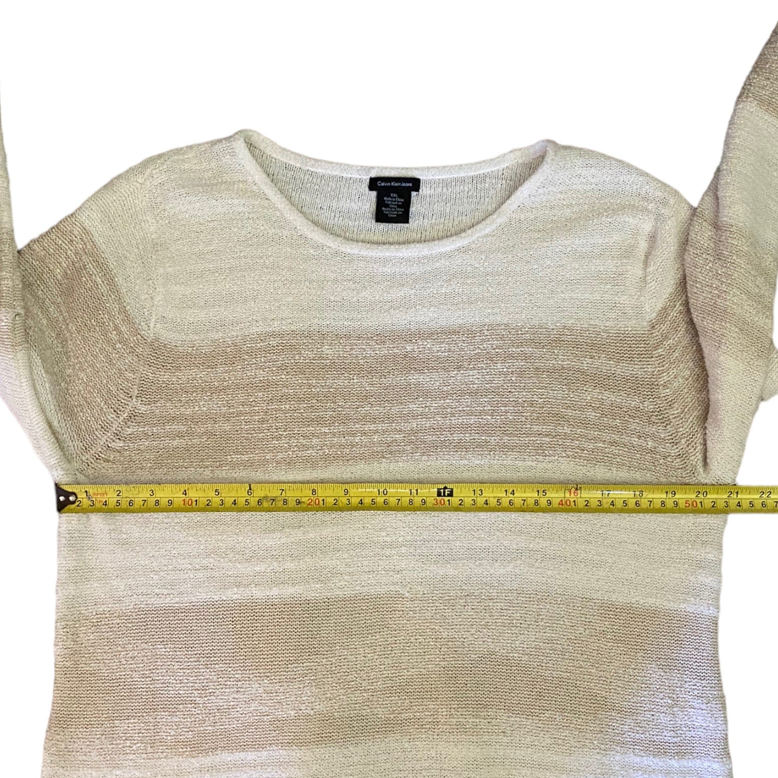 Beige knit top with a measuring tape on a white background