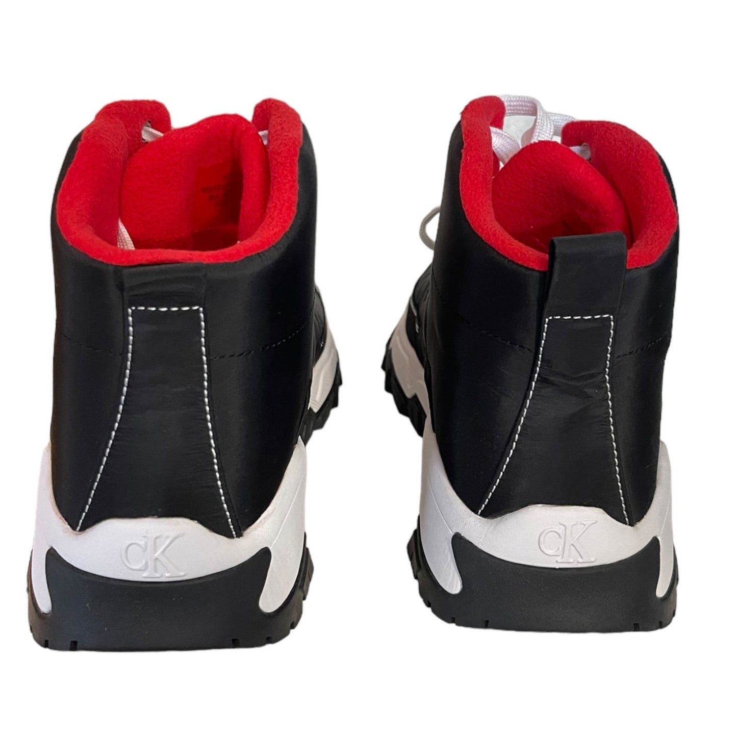A pair of black high-top sneakers shown from the back, featuring a bright red interior lining, white stitching, and a white and black sole with a visible 'ck' logo on the heel.