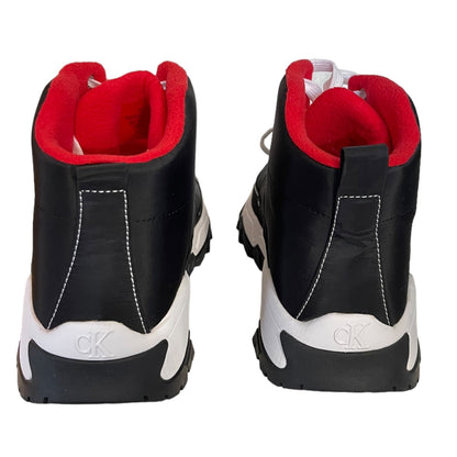 A pair of black high-top sneakers shown from the back, featuring a bright red interior lining, white stitching, and a white and black sole with a visible 'ck' logo on the heel.