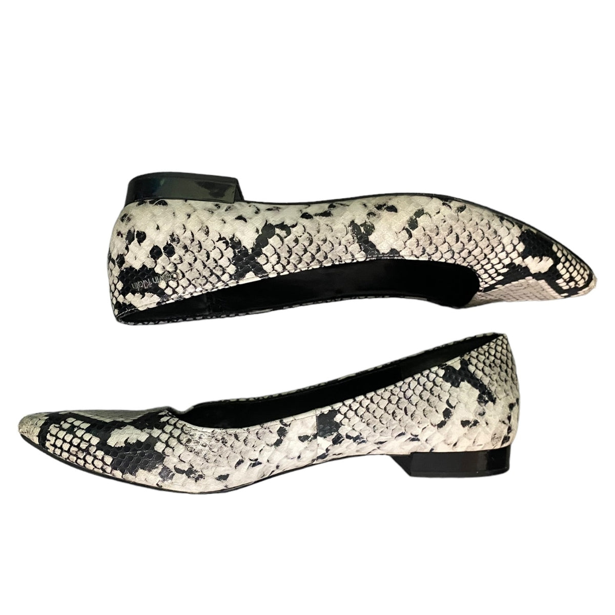 A pair of pointed-toe flat shoes with a black and off-white snakeskin pattern, shown from side and top angles against a plain white background.