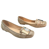 Side view of Pair of gold flat shoes with decorative buckle on a white background