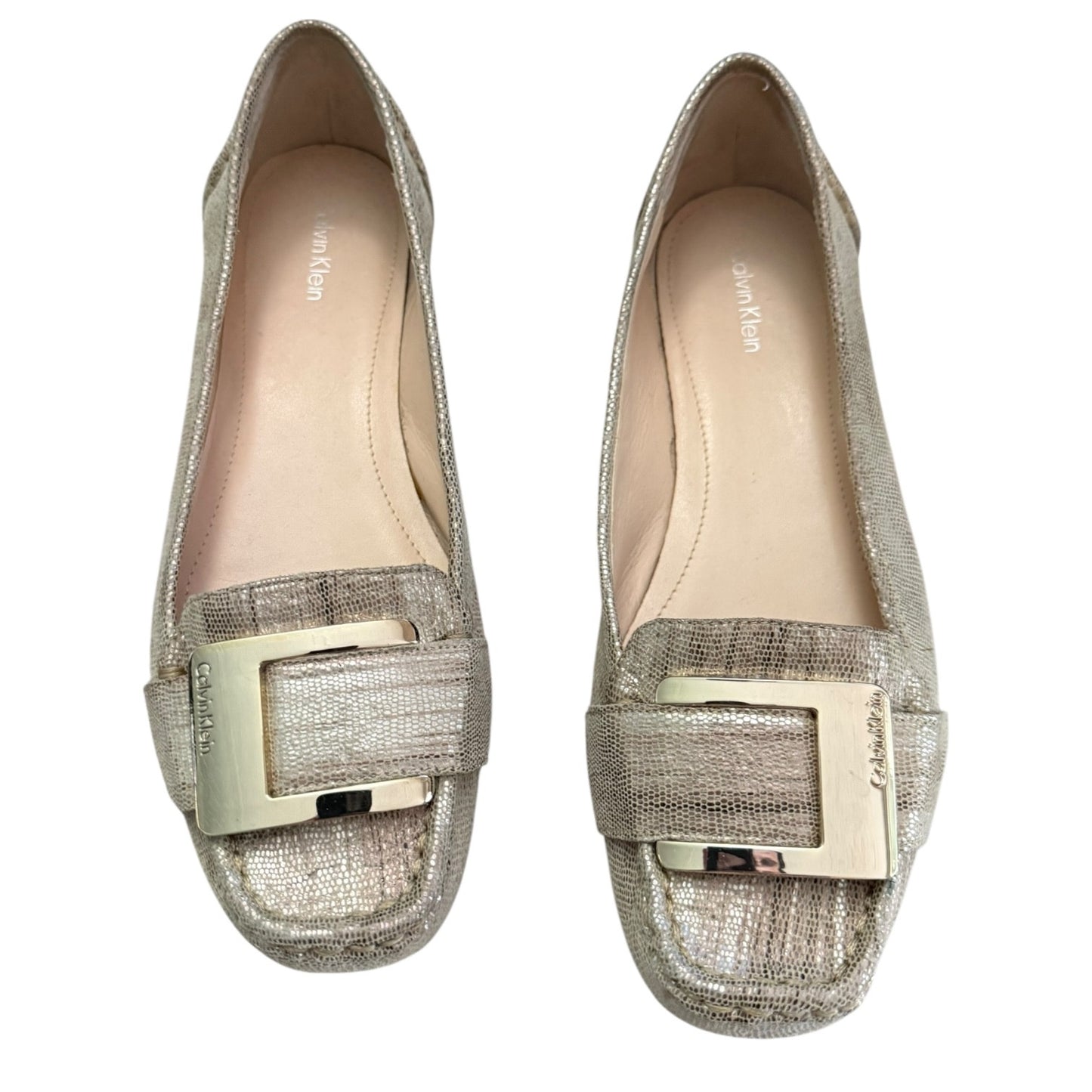 Front of gold loafers with gold buckles on a white background