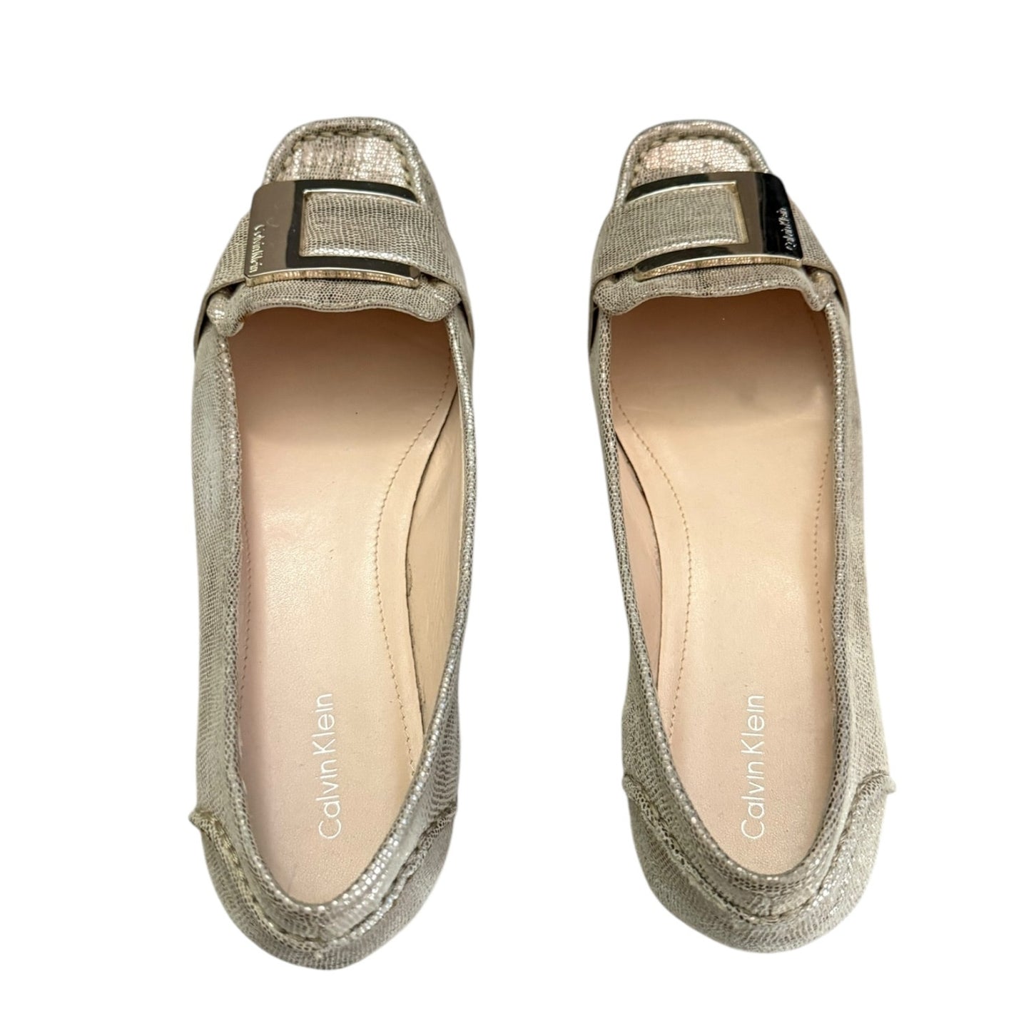 Top of gold loafers with a visible brand logo on a white background