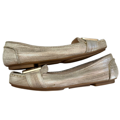 Side of gold metallic loafers on a white background