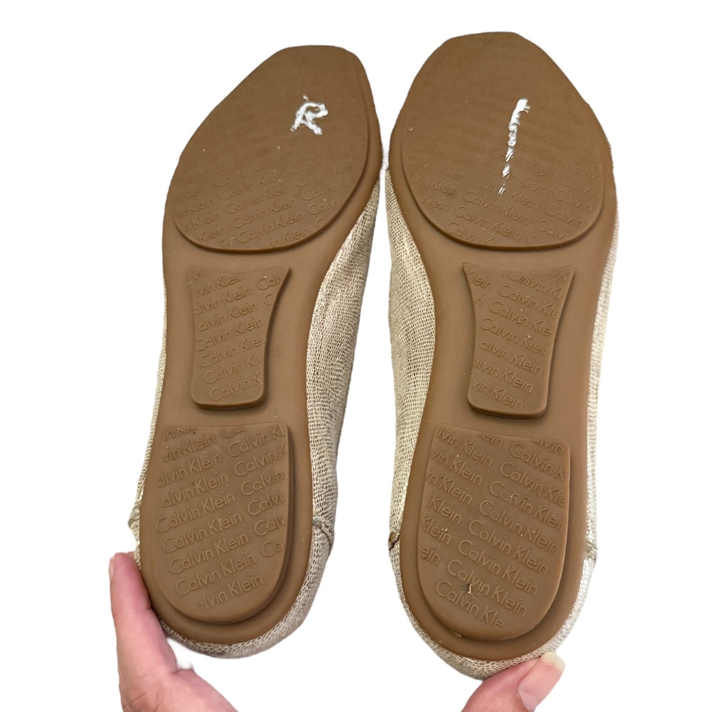 Bottom of shoes soles held by a hand on a white background