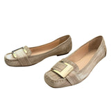 Pair of gold loafers with gold buckles on a white background