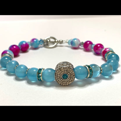 Bracelet with blue and pink beads and a decorative charm on a white background
