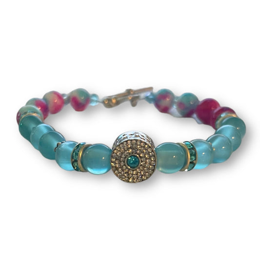 Blue pink beaded bracelet with a decorative charm on a white background