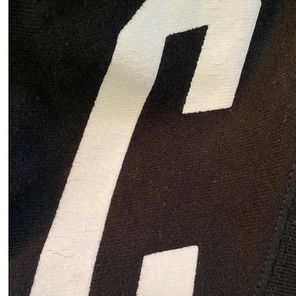 Close-up of a black fabric with a large white letter 'C' on a black background