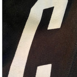 Close-up of a black fabric with a large white letter 'C' on a black background