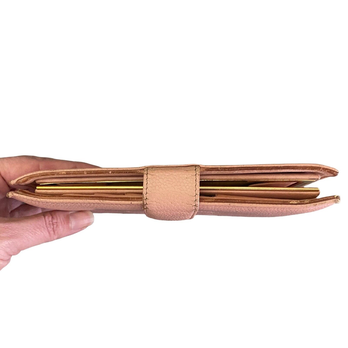 Hand holding a pink leather wallet with gold accents on a white background