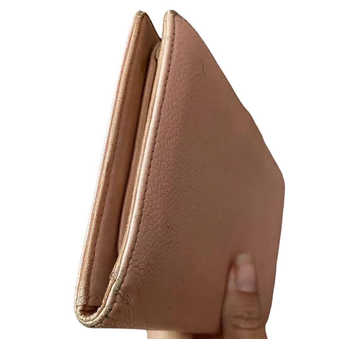 Close-up of corners on a pink leather wallet held by a hand on a white background