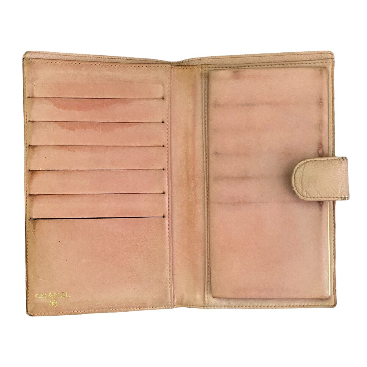 An open vintage pink leather wallet with multiple card slots on the left and a slip pocket on the right, featuring a small gold 'CHANEL' logo on the bottom left.